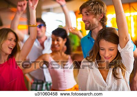 Stock Photo - Friends dancing with arms up in bar. Fotosearch