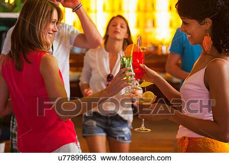 Stock Image - Friends drinking cocktails in bar. Fotosearch
