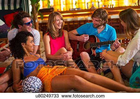 Stock Image - Friends enjoying guitar playing in bar. Fotosearch