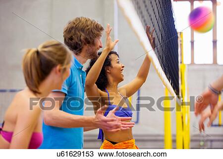 Stock Image - Friends enjoying indoor beach volleyball. Fotosearch
