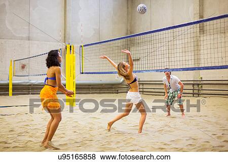 Stock Photo - Friends playing indoor beach volleyball. Fotosearch