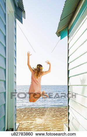 Girl mid air in front of beach huts View Large Photo Image Stock Image - Girl mid air in front of beach huts. Fotosearch