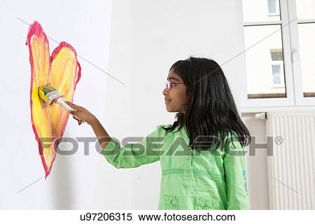 Stock Photography - Girl painting heart shape on wall. Fotosearch