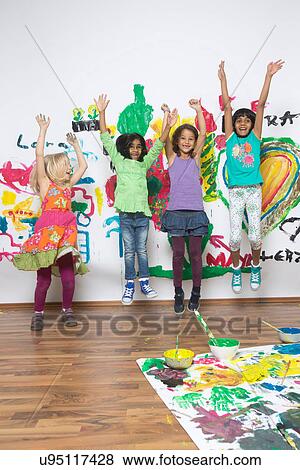 Girls jumping in front of painted wall View Large Photo Image Stock Photo - Girls jumping in front of painted wall. Fotosearch
