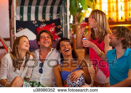 Group of friends blowing bubbles at indoor beach party View Large Photo Image Stock Image - Group of friends blowing bubbles at indoor beach party. Fotosearch