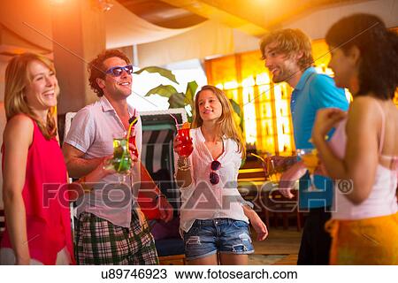 Stock Image - Group of friends dancing in bar. Fotosearch