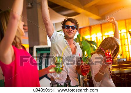 Group of friends dancing with cocktails in bar View Large Photo Image Stock Image - Group of friends dancing with cocktails in bar. Fotosearch