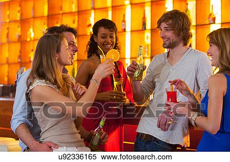 Stock Photography - Group of friends enjoying drinks in bar. Fotosearch