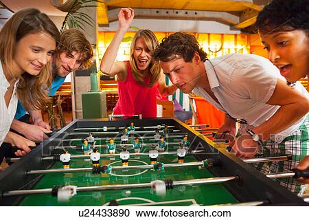 Group of friends playing table football View Large Photo Image Stock Image - Group of friends playing table football. Fotosearch