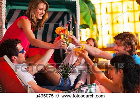 Stock Photo - Group of friends with cocktails at indoor beach party. Fotosearch