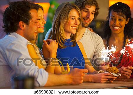 Stock Image - Group of friends with cocktails in bar. Fotosearch