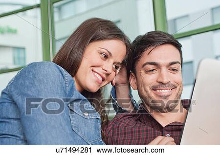 Stock Image - Happy young couple looking at digital tablet. Fotosearch