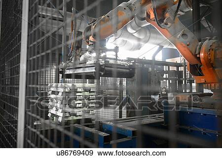 Stock Photo - Heavy machinery lifting metal ingots at aluminum recycling plant. Fotosearch