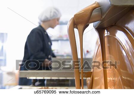 Stock Photography - Liquid chocolate running through machine in sweet factory. Fotosearch