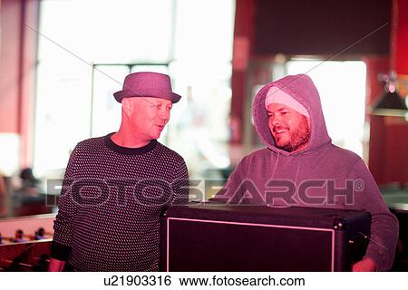 Stock Photograph - Man carrying speaker into club. Fotosearch