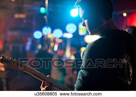 Stock Photography - Man on stage playing guitar in nightclub. Fotosearch