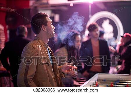 Man smoking cigarette in bar View Large Photo Image Stock Photograph - Man smoking cigarette in bar. Fotosearch