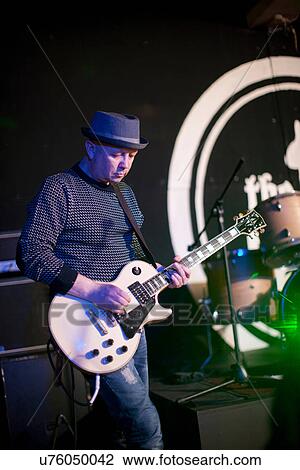 Stock Image - Mature man playing guitar on stage. Fotosearch