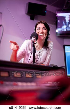Stock Image - Mid adult woman broadcasting in recording studio. Fotosearch