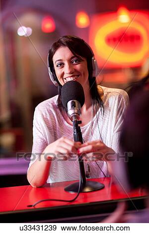 Stock Photo - Mid adult woman broadcasting in recording studio. Fotosearch