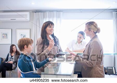 Stock Photography - Mother and son making payment at hospital reception. Fotosearch