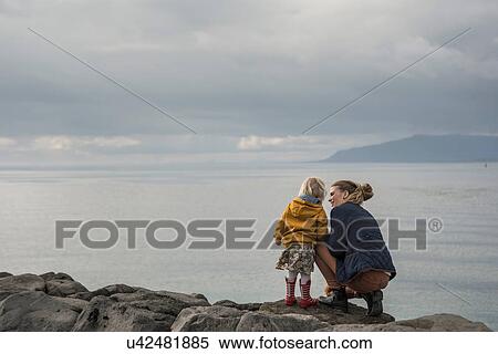 Mother and toddler crouching on harbor wall View Large Photo Image Stock Photography - Mother and toddler crouching on harbor wall. Fotosearch