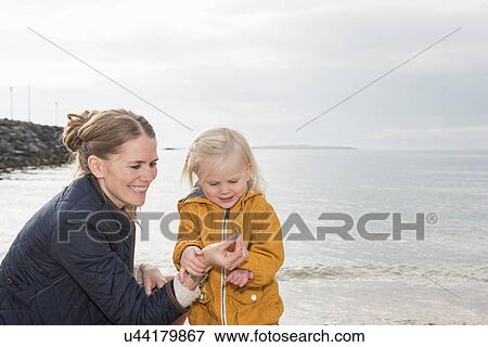 Stock Photo - Mother and toddler exploring at coast. Fotosearch