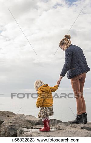 Stock Image - Mother and toddler walking on harbor wall. Fotosearch