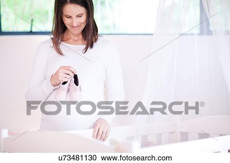 Mother holding baby booties on her bump View Large Photo Image Stock Image - Mother holding baby booties on her bump. Fotosearch