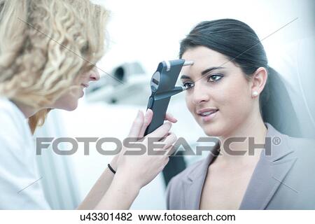Stock Image - Optician examining patient in eye clinic. Fotosearch