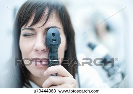 Optician looking through ophthalmoscope View Large Photo Image Stock Image - Optician looking through ophthalmoscope. Fotosearch