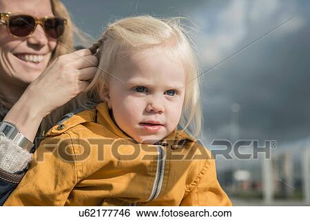 Stock Photograph - Outdoor portrait of mother braiding toddlers hair. Fotosearch