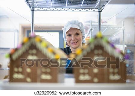 Stock Image - Portrait of chocolatier standing behind chocolate houses. Fotosearch