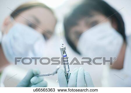 Portrait of dentist and dental nurse holding syringe View Large Photo Image Stock Image - Portrait of dentist and dental nurse holding syringe. Fotosearch