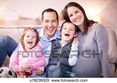 Stock Photo - Portrait of expectant couple with two young children. Fotosearch