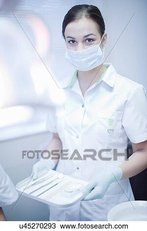 Stock Image - Portrait of female dental nurse holding surgical tray. Fotosearch