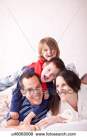 Portrait of parents and two young children on bed View Large Photo Image Stock Photo - Portrait of parents and two young children on bed. Fotosearch