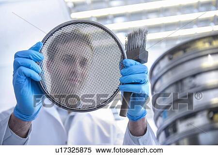 Stock Photography - Portrait of scientist holding metal brush and sieve. Fotosearch
