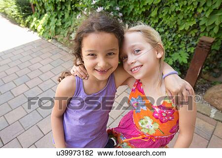 Stock Image - Portrait of two girls hugging. Fotosearch