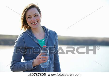Stock Photography - Portrait of young woman at coast taking exercise break. Fotosearch
