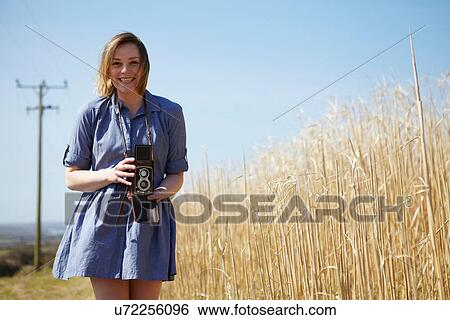 Stock Photograph - Portrait of young woman holding camera. Fotosearch