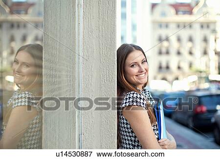 Portrait of young woman holding files outside city office View Large Photo Image Stock Photo - Portrait of young woman holding files outside city office. Fotosearch
