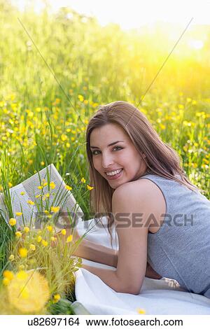 Portrait of young woman reading in field of buttercups View Large Photo Image Picture - Portrait of young woman reading in field of buttercups. Fotosearch