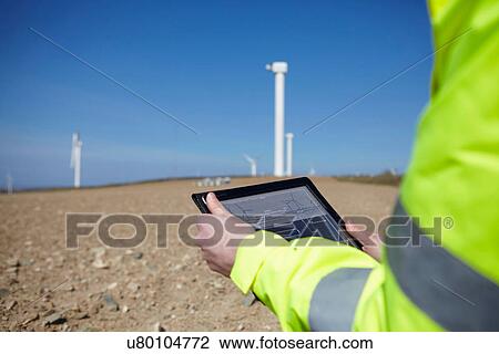 Stock Image - Project manager using digital tablet in front of wind farm. Fotosearch