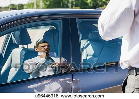 Stock Photograph - Reflection of businessman adjusting his tie. Fotosearch