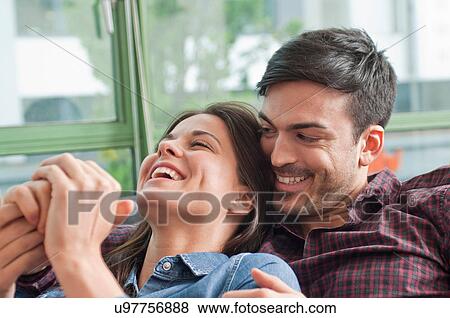 Romantic young couple laughing on sofa View Large Photo Image Stock Photo - Romantic young couple laughing on sofa. Fotosearch