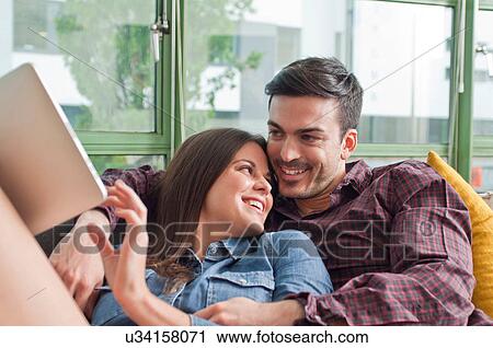 Romantic young couple on sofa with digital tablet View Large Photo Image Stock Image - Romantic young couple on sofa with digital tablet. Fotosearch
