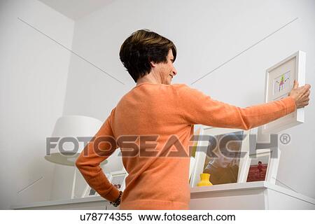 Senior woman arranging family photographs View Large Photo Image Stock Photography - Senior woman arranging family photographs. Fotosearch