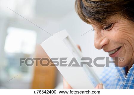 Stock Image - Senior woman holding picture frame. Fotosearch