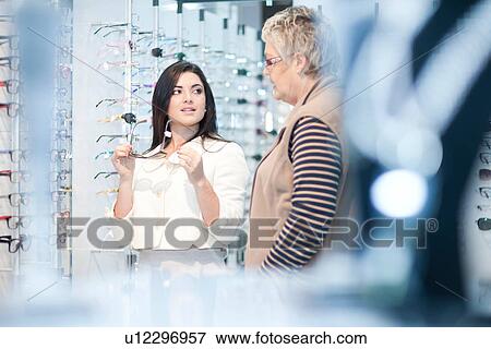 Shop assistant and client in opticians shop View Large Photo Image Stock Photo - Shop assistant and client in opticians shop. Fotosearch